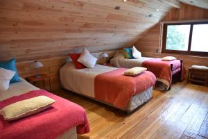 1 dormitorio con 2 camas en una cabaña de madera en Cabañas Raki, en Frutillar