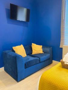un sofá azul con almohadas amarillas en la sala de estar. en En-suite near Stratford in a guesthouse, en Londres