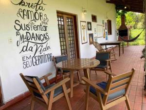 une table et des chaises devant un restaurant dans l'établissement Casa de Fazenda na Ecovila Sustentar, 38km de SP, à Embu-Guaçu