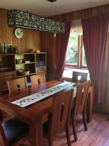 comedor con mesa de madera y sillas en Cabañas Raki, en Frutillar