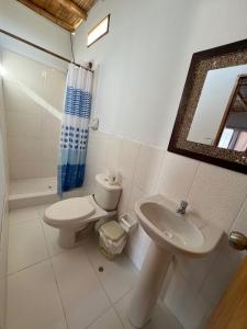 uma casa de banho com um WC, um lavatório e um espelho. em Pocitas Casa Hotel - Playa & Piscina em Máncora