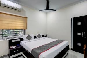 a bedroom with a bed and a window at Townhouse Majestic Inn in Chennai