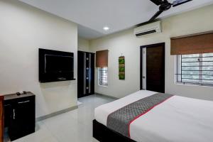 Schlafzimmer mit einem Bett und einem Flachbild-TV in der Unterkunft Townhouse Majestic Inn in Chennai