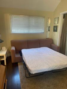 a bed in a room with a couch and a window at Downtown N. Vancouver Lane home in North Vancouver