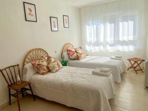 1 dormitorio con 2 camas, silla y ventana en -.Villa Nena 2.0.- en Ledesma