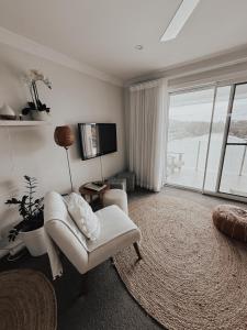 a living room with a white chair and a large window at Diggers Beach Villa Coffs Harbour in Coffs Harbour