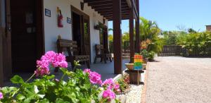 a porch of a house with some pink flowers at Pousada Gauleses - Refugio de Charme na Praia do Rosa by La Vem Férias in Praia do Rosa