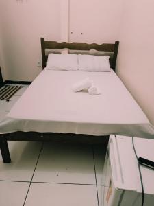 een bed in een kamer met witte lakens en kussens bij Hotel e Lanchonete Bom Gosto in Bom Jesus da Lapa