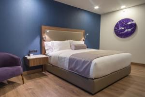 a bedroom with a large bed and a purple wall at Sheraton Guadalajara Expo in Guadalajara