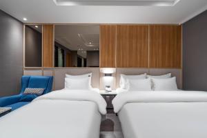 Zimmer mit 2 Betten und einem blauen Stuhl in der Unterkunft Jecheon The Wall Hotel in Jecheon