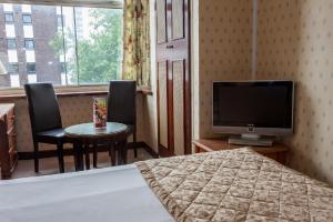 a hotel room with a television and a table and chairs at Hampstead Britannia in London