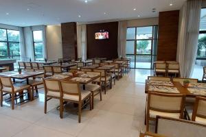 a restaurant with wooden tables and chairs and a television at Apto Flat Midas na Via Olímpica Encantador in Rio de Janeiro