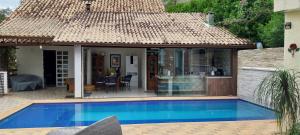 a villa with a swimming pool in front of a house at Casa de Campo - Vista da montanha in Itaipava