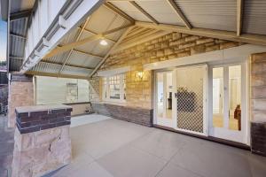 a large room with a stone wall and a patio at Glenelg Beach Bungalow in Glenelg