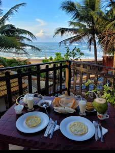 uma mesa com pratos de comida e a praia em SUNSET Cabana em Galle