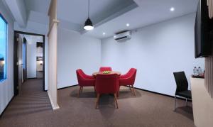 a dining room with red chairs and a table at NEO+Waru-Sidoarjo by ASTON in Sidoarjo