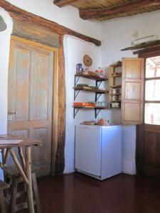 a kitchen with a white refrigerator and a door at La Calabaza Cabaña in Tilcara