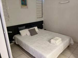 um quarto com uma cama com lençóis brancos e almofadas em Le 63* em La Trinité