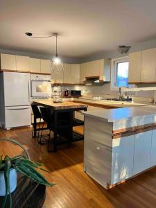uma cozinha com uma mesa e um frigorífico branco em Spacious 4 Bedroom Forest Escape [Sunroom+Firepit] em Kawartha Lakes
