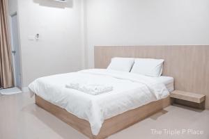 um quarto branco com uma cama com lençóis brancos em The Triple P Place เดอะ​ทริปเปิลพีเพลส em Ban Non Sung