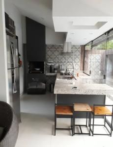 a kitchen with a counter and some chairs in it at Casa de Campo - Vista da montanha in Itaipava