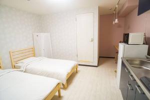 Duas camas numa cozinha com um lavatório e um frigorífico. em Direct to Namba,Korean town102 em Osaka