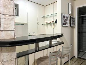 a kitchen with white cabinets and a counter with two chairs at Flat number one temporadalitoranea in São Luís