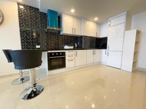 a kitchen with white cabinets and a bar stool in it at Large 2 BR Condo, Grand Avenue, Central Pattaya in Pattaya