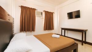 a small bedroom with a bed and a television at WestCourt Inn Ilocos Sur in Bantaoay