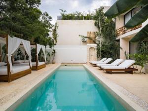 a swimming pool with chaise lounge chairs next to a house at Villa Sorella in Aldea Zama 24Hrs Security, 5min to the beach in Tulum