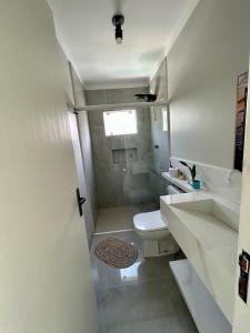 y baño blanco con ducha y aseo. en bnb Praia Mole, Barra totalmente quintal privativo, en Florianópolis