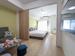 ESLEAD HOTEL Namba South Ⅲ في أوساكا: غرفه فندقيه بسرير واريكه