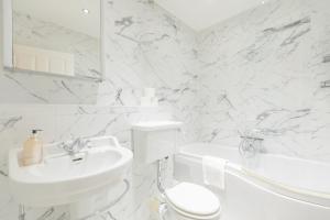 a white bathroom with a sink and a toilet at Newly Refurbished 2BD Flat - Wimbledon Village! in London