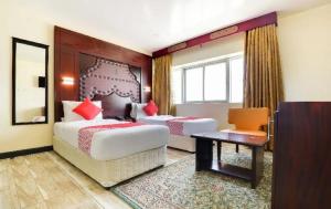 a hotel room with two beds and a desk at SHH Hotel in Fujairah