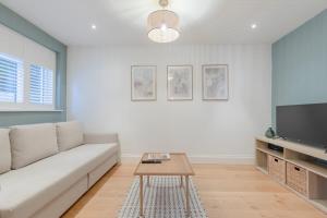 a living room with a couch and a tv at Newly Refurbished 2BD Flat - Wimbledon Village! in London