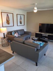 a living room with a couch and a flat screen tv at Pandanus Coolum Beach in Coolum Beach