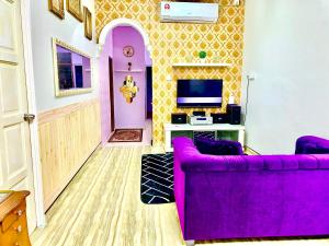 een paarse bank in een woonkamer met een tv bij Danisha Homestay in Kampong Baru