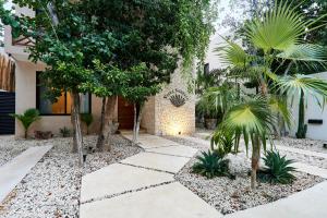 a garden with palm trees and a walkway at Villa Sorella in Aldea Zama 24Hrs Security, 5min to the beach in Tulum