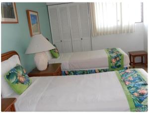 een slaapkamer met 2 bedden en een lamp op een tafel bij Hawaiian Hospitality in Honolulu