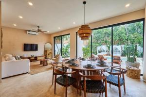 a dining room and living room with a table and chairs at Villa Sorella in Aldea Zama 24Hrs Security, 5min to the beach in Tulum