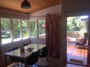 a dining room with a table and chairs and windows at Nikau Retreat in New Plymouth