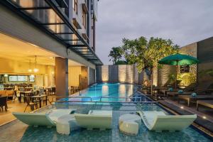 a large swimming pool with chairs and tables at Kamaniiya Petitenget Seminyak in Seminyak