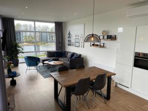 ein Wohnzimmer mit einer Couch und einem Tisch und Stühlen in der Unterkunft Marina Strandbad Chalet Aan het Water mit Zaun Haus Nr 134 in Olburgen