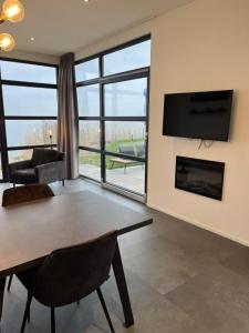 a living room with a dining table and a fireplace at Enkhuizer Strand Chalet Strandmuschel Erste Reihe Hausnr 215 in Enkhuizen