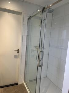 een douche met een glazen deur in de badkamer bij Enkhuizer Strand Chalet Meeresbrise Dritte Reihe mit Zaun Haus Nr 251 in Enkhuizen