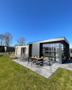 una casa di vetro con tavolo e sedie in un campo di Enkhuizer Strand Chalet Sunkiss Dritte Reihe Haus Nr 217 a Enkhuizen