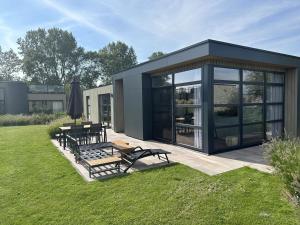 una pequeña casa negra con mesa de picnic y bancos en Enkhuizer Strand Chalet MeerZeit Dritte Reihe Haus Nr 212, en Enkhuizen