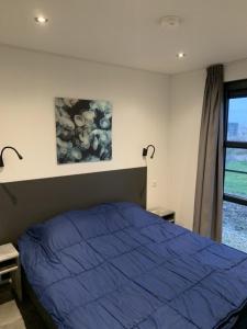 a bedroom with a blue bed and a window at Enkhuizer Strand Chalet Meeresrauschen Erste Reihe mit Zaun Haus Nr 249 in Enkhuizen