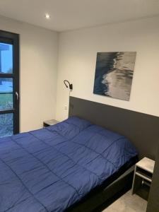 a bedroom with a blue bed and a window at Enkhuizer Strand Chalet Meeresrauschen Erste Reihe mit Zaun Haus Nr 249 in Enkhuizen