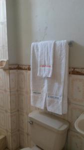 Deux serviettes sont suspendues au-dessus des toilettes dans la salle de bains. dans l'établissement Casa del Huesped - Guest House, à Pucallpa